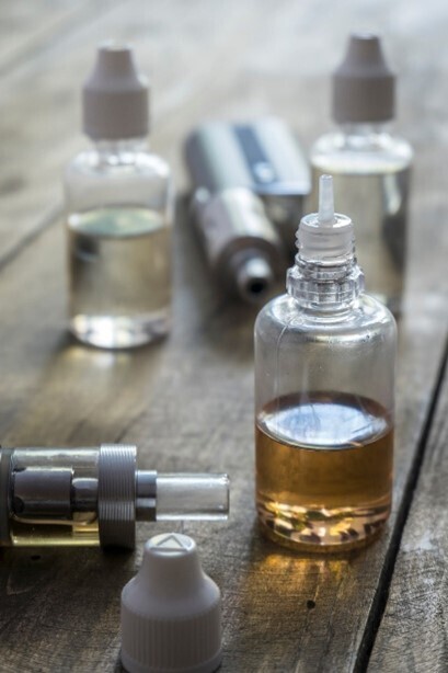 E-Zigaretten und verschiedene Liquids, die nebeneinander auf einem Tisch liegen