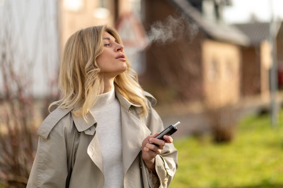 Frau, die in einer Wohnsiedlung eine Vape raucht