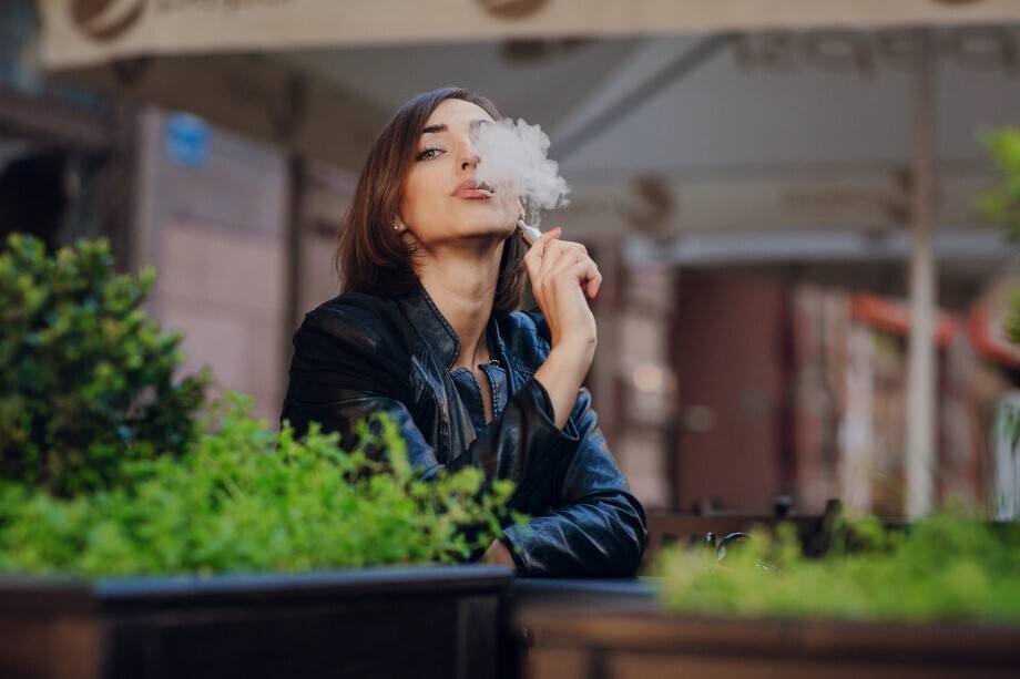 Frau, die in einem Café sitzend eine E-Shisha raucht