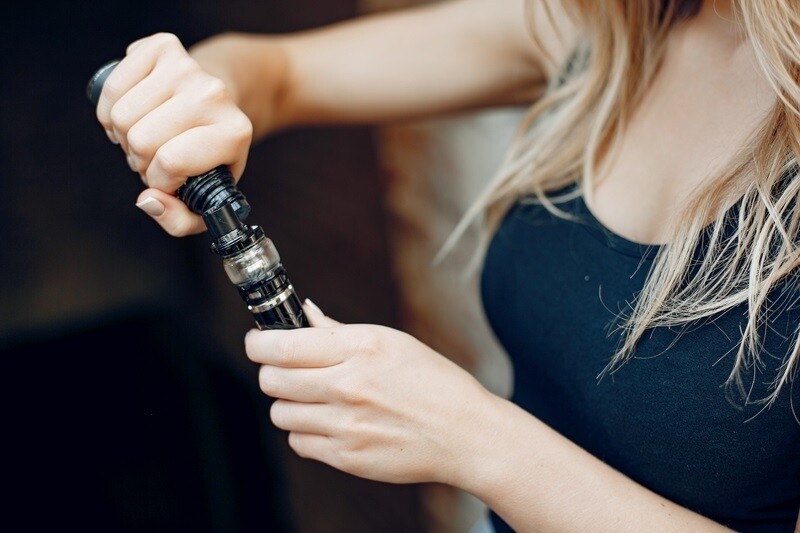 Frau füllt Liquid in eine E-Zigarette ein