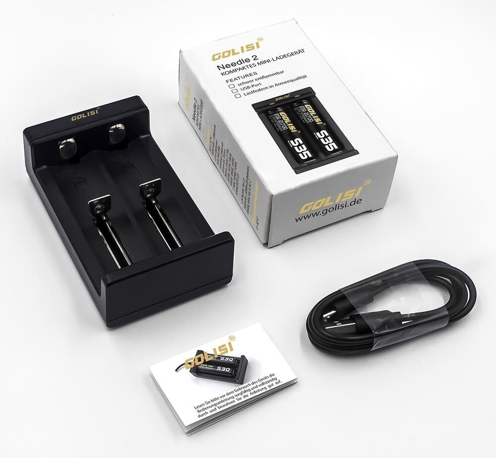 Golisi Needle 2 Ladegerät 2-Schacht Golisi Needle 2 Ladegerät mit zwei Schachtplätzen, Verpackung, Ladekabel und Anleitung auf weißem Hintergrund.